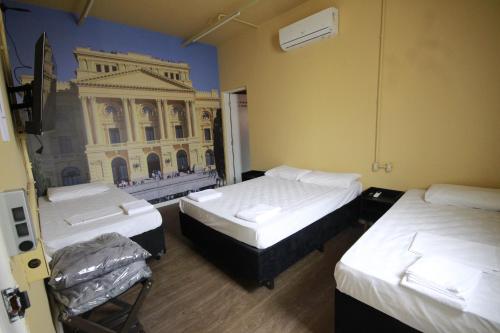 two beds in a room with a building on the wall at Hostel Distrito 011 in Sao Paulo