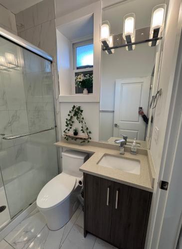 a bathroom with a toilet and a sink and a shower at Sweet home 2 bedroom suite in Surrey