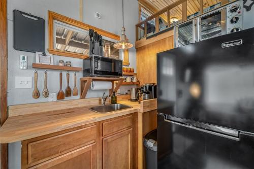 a kitchen with a sink and a black refrigerator at Tiny Cub House with Fast WiFi and Dog Friendly in Mentone