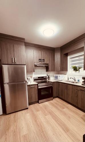 a kitchen with wooden cabinets and a stainless steel refrigerator at Sweet home 2 bedroom suite in Surrey