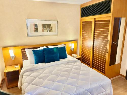 a bedroom with a large white bed with blue pillows at Hotel São Paulo - Avenida Paulista in Sao Paulo