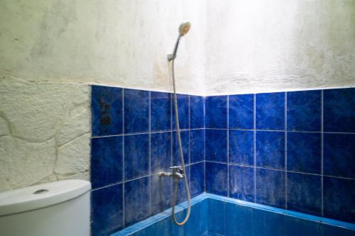 a blue tiled bathroom with a shower and a toilet at OYO 94118 Homestayque Syariah in Cimahi