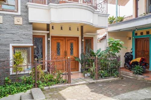 a house with a wooden door and a fence at OYO 94118 Homestayque Syariah in Cimahi