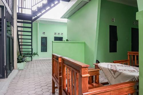 班达楠榜OYO 93695 Guest House Riharti Syariah的一间设有木凳和绿色墙壁的客房