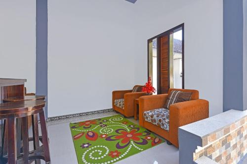 a living room with orange chairs and a green rug at Hotel O Homestay Antara in Gilimanuk