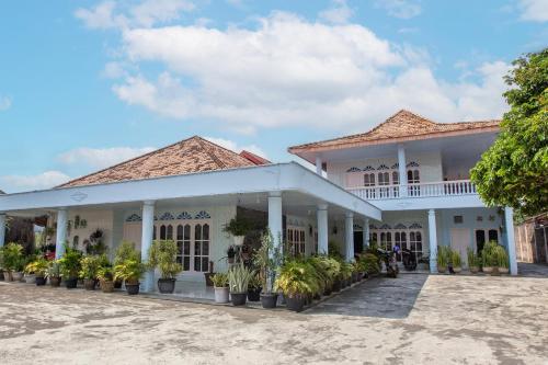 a white building with potted plants in the courtyard at OYO Life 92803 Penginapan Purnama in Kayuagung