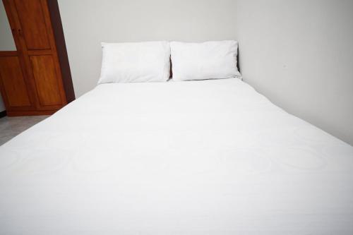 a white bed with two pillows on top of it at OYO Life 93045 Kost Putra Bu Ketut in Lumajang