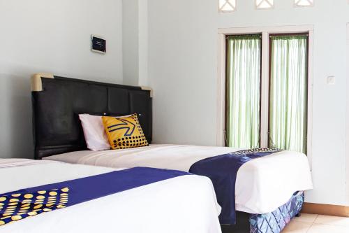 two beds sitting next to each other in a bedroom at Hotel O Delta Bnb Residence Syariah in Prabumulih