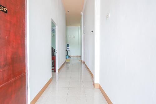 a hallway with white walls and a white tile floor at Hotel O Delta Bnb Residence Syariah in Prabumulih