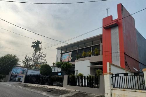 a red and white building with a fence at Hotel O Rumah Singgah Cemara Syariah in Pekanbaru