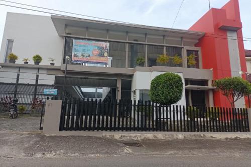 a red and white building with a black fence at Hotel O Rumah Singgah Cemara Syariah in Pekanbaru