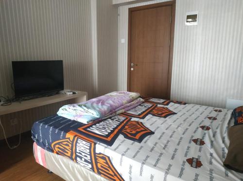 a bedroom with a bed with a television on a table at OYO Life 92745 The Margo Monthly Stay in Depok
