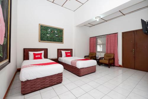a hotel room with two beds and a table at SUPER OYO Capital O 1644 Hotel Griya Kencana in Solo