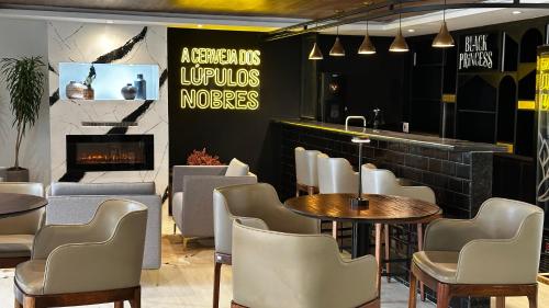 a restaurant with tables and chairs and a fireplace at Gran Paradiso Campos do Jordão By Ventura OFICIAL in Campos do Jordão