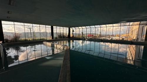 a large swimming pool in a building with windows at Gran Paradiso Campos do Jordão By Ventura OFICIAL in Campos do Jordão