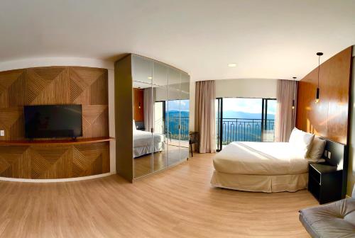 a hotel room with a bed and a flat screen tv at Gran Paradiso Campos do Jordão By Ventura OFICIAL in Campos do Jordão