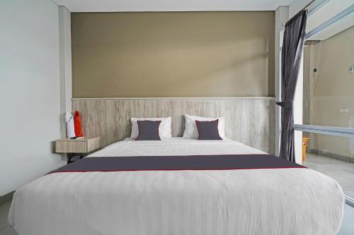 a large white bed with purple pillows in a bedroom at Capital O 1898 Louise Place in Cianjur