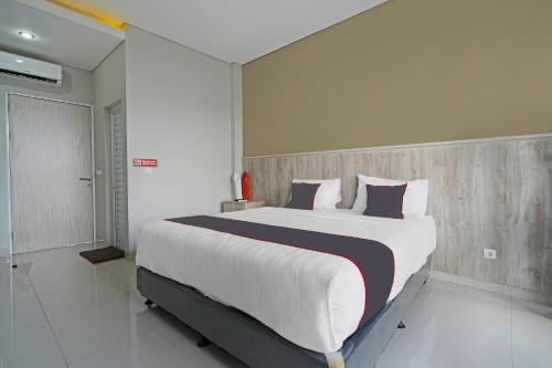 a bedroom with a large white bed with purple pillows at Capital O 1898 Louise Place in Cianjur