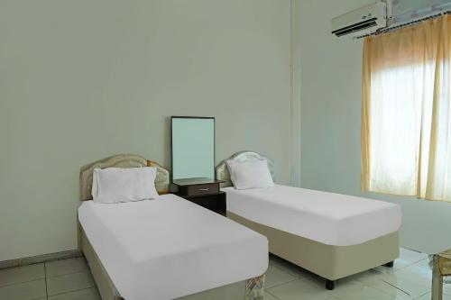 2 camas blancas en una habitación con espejo en Hotel O Wilma Kost Syariah, en Banjarmasin