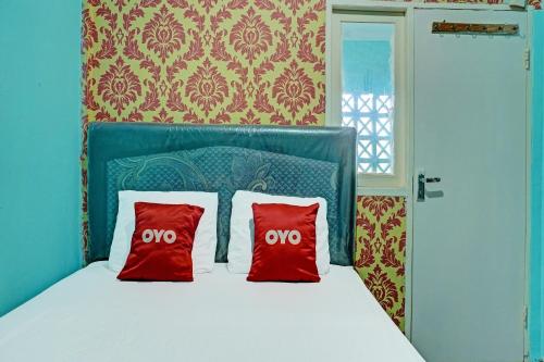 a bedroom with a bed with two red pillows at Hotel O Home Stay Elis Cateliya Syariah in Karawang
