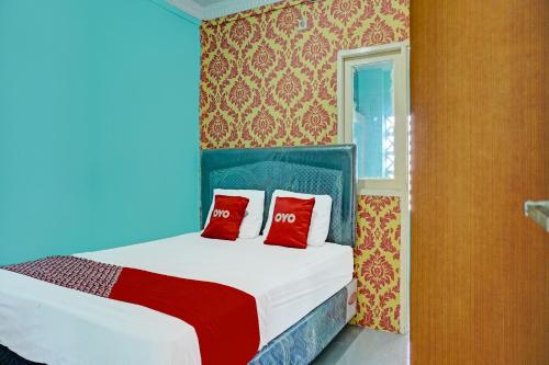 a bedroom with a bed with two red pillows at Hotel O Home Stay Elis Cateliya Syariah in Karawang
