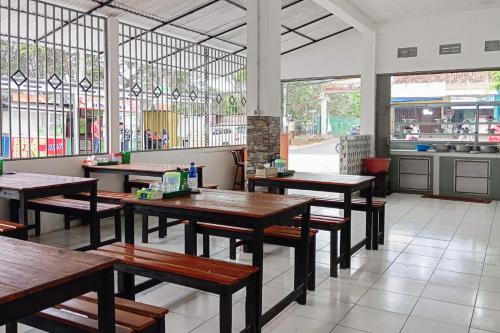 a restaurant with wooden tables in a room with windows at Hotel O Homestay Jaya Putri 1 Syariah in Bandar Lampung