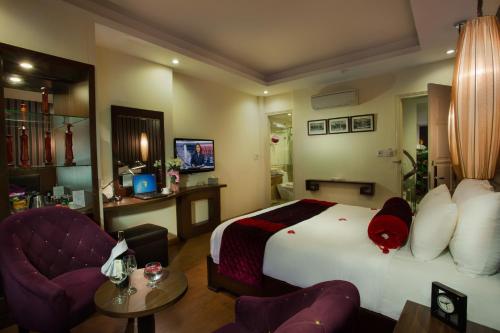 a hotel room with a bed and two chairs at Golden Art Hotel in Hanoi