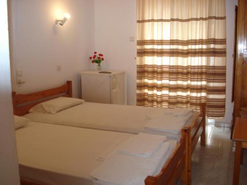 1 dormitorio con 2 camas y una ventana con flores en Filio Sevastatou Rooms, en Therma