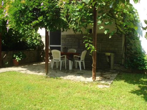 una mesa y sillas bajo un árbol en un patio en Filio Sevastatou Rooms, en Therma