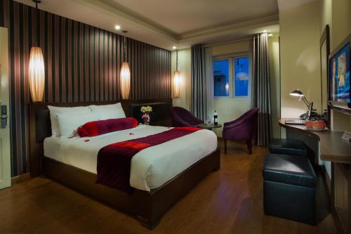 a hotel room with a large bed and a desk at Golden Art Hotel in Hanoi