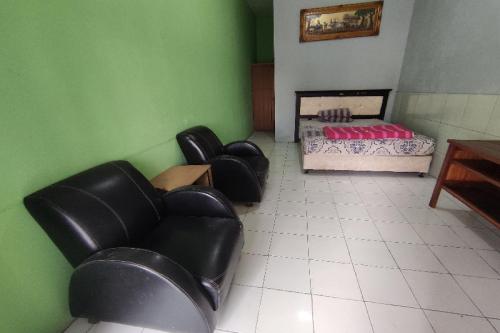 a room with two leather chairs and a bed at SPOT ON 91105 Hotel Salsabila in Magelang