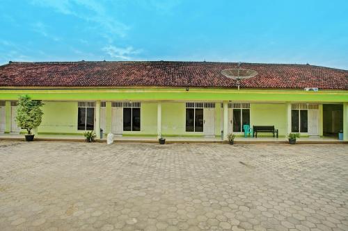 a large yellow building with a red roof at Hotel O Sejahtera Syariah in Umbulan Tulungmeris