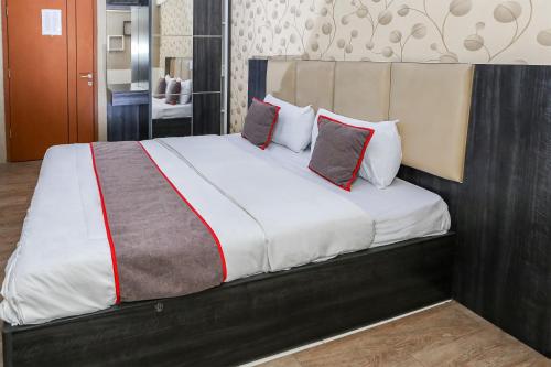 a bedroom with a large bed with two pillows at Capital O 93372 Aurora Residence in Tangerang