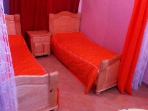 2 letti singoli in una camera con tende rosse di Maison de Vacances a Saïdia