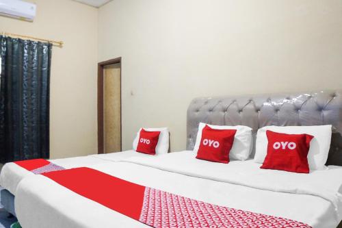 a bedroom with a large bed with red pillows at Hotel O Sky Residence Mawar in Sunggal