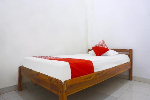 a small bed with red and white pillows on it at Hotel O Almeerah Homestay Syariah Near RS Hermina in Pampang