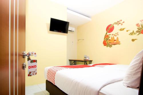 a hotel room with two beds and a flat screen tv at Capital O 217 A1 Hotel in Surabaya