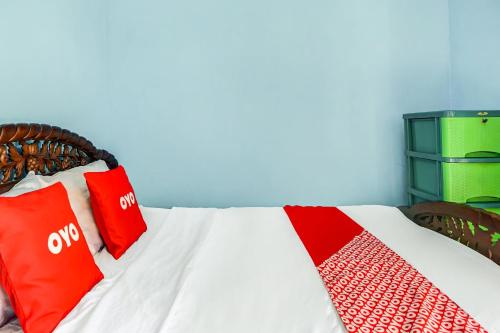 a bed with red and white pillows on it at OYO Life 90879 Ara Predator Funpark in Batu