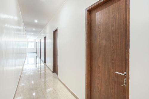 un corridoio con porta in legno e pareti bianche di Capital O 134 Lg Residence a Surabaya