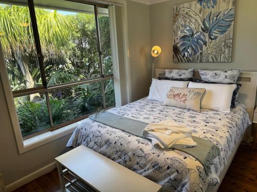 a bedroom with a bed and a large window at Frogs by the Sea in Cronulla