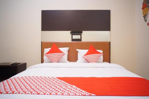 a bed with red and white pillows on it at Hotel O near Universitas Widya Dharma formerly Nugraha Residence in Talang Kelapa