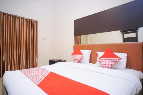 a bedroom with a bed with red and orange pillows at Hotel O near Universitas Widya Dharma formerly Nugraha Residence in Talang Kelapa