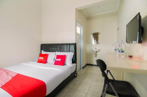 a bedroom with a bed with red pillows and a desk at Hotel O Fakhira Residence in Tjiandjur