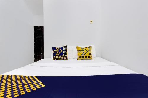 a bed with yellow and blue pillows on it at Hotel O Orchid Guest House in Yogyakarta