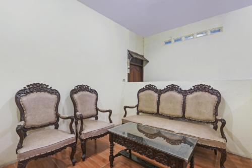 two chairs and a coffee table in a room at Hotel O Alika Homestay in Demak