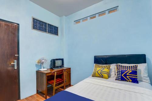a bedroom with a bed and a tv on a table at Hotel O Alika Homestay in Demak