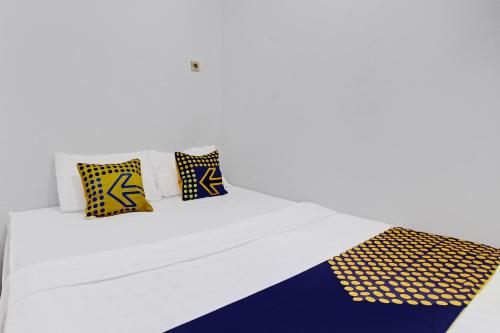 a white bed with four pillows on it at Hotel O Orchid Guest House in Yogyakarta