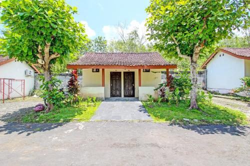 a house with a driveway and trees in front of it at Hotel O Orchid Guest House in Yogyakarta