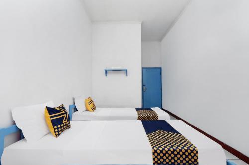 a white bed with yellow and blue pillows on it at Hotel O Saudara in Tegal
