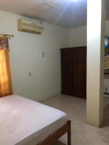 a bedroom with a white bed and a wooden cabinet at Hotel O Rumah Oma Syariah in Kupang